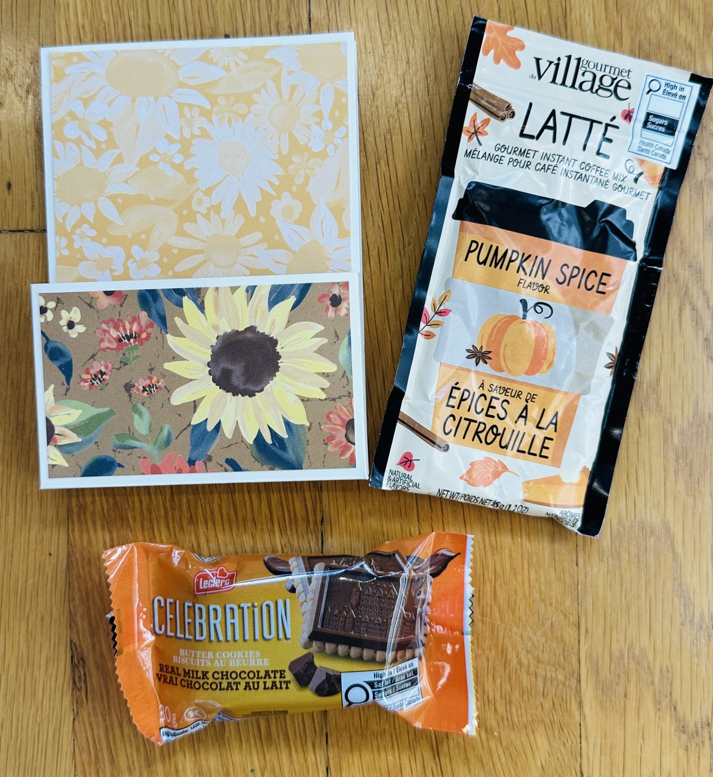 Fall treat holder card next to a pumpkin spice latte sachet and a wrapped chocolate butter cookie, the treats that fit in the front pocket
